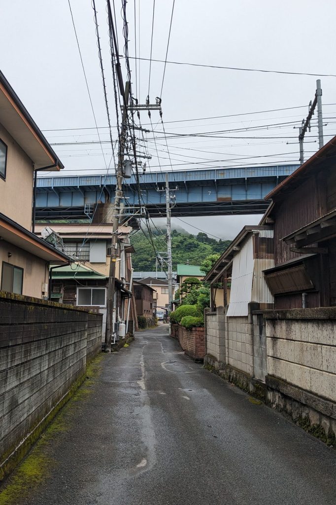 A narrow street below electrical cables and a rail bridge.